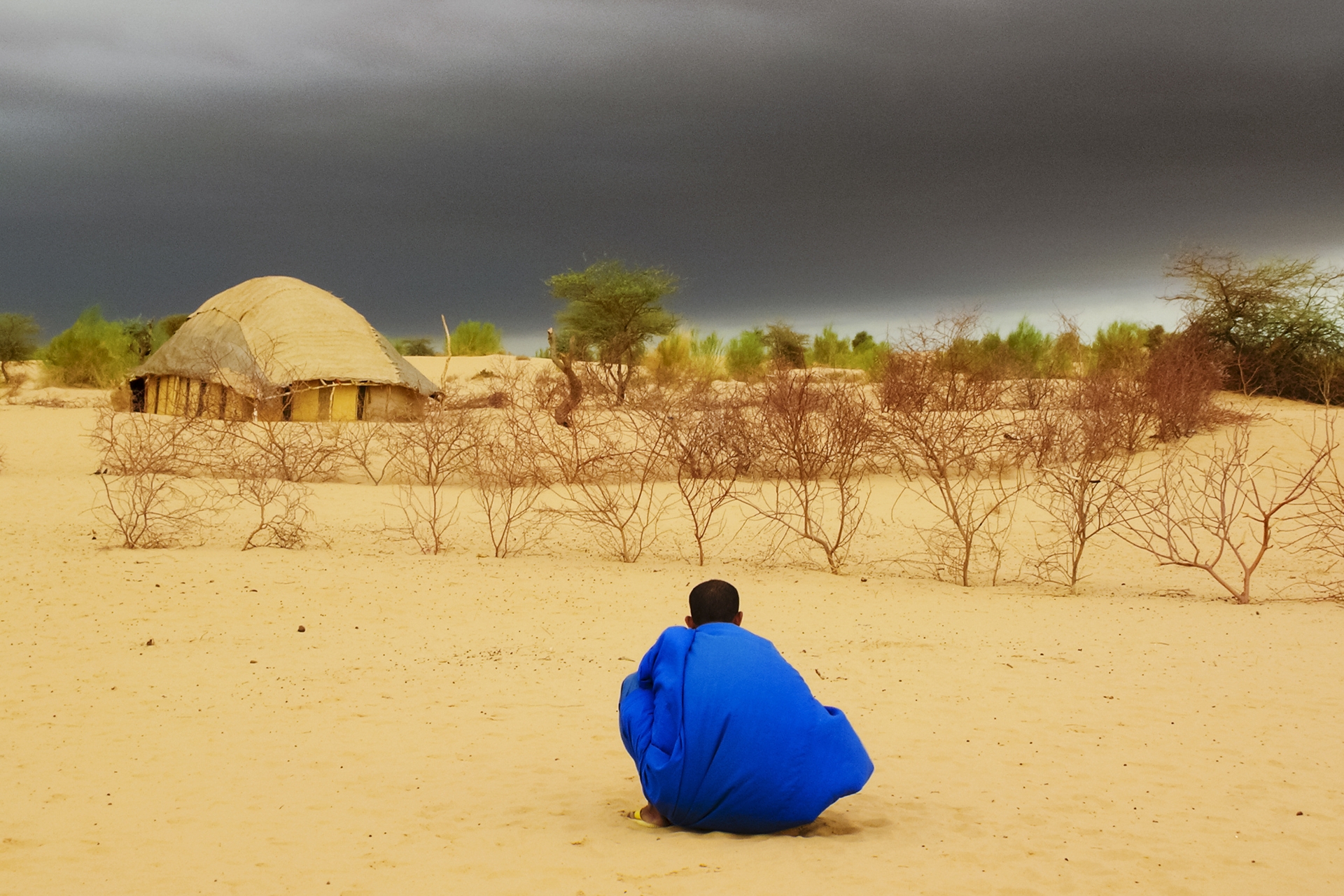 Tuareg man in the desert stalking at dark clouds waiting for the rain.